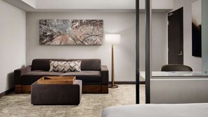 A modern hotel room with a sofa, ottoman, floor lamp, and a large abstract painting on the wall. - Near Great America Theme Park + Breakfast & Pool (Milpitas)
