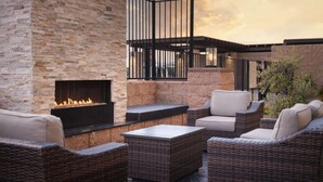 An outdoor patio with wicker furniture, a stone wall, and a fireplace. - Near Great America Theme Park + Breakfast & Pool (Milpitas)