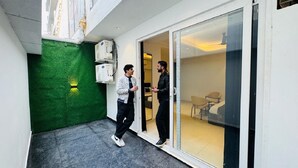 A modern interior with a glass door leading to a room with a chair and a table. - Reebah Inn & Suites (Gurugram)