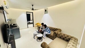 A modern living room with a sofa, a coffee table, and a TV. - Reebah Inn & Suites (Gurugram)