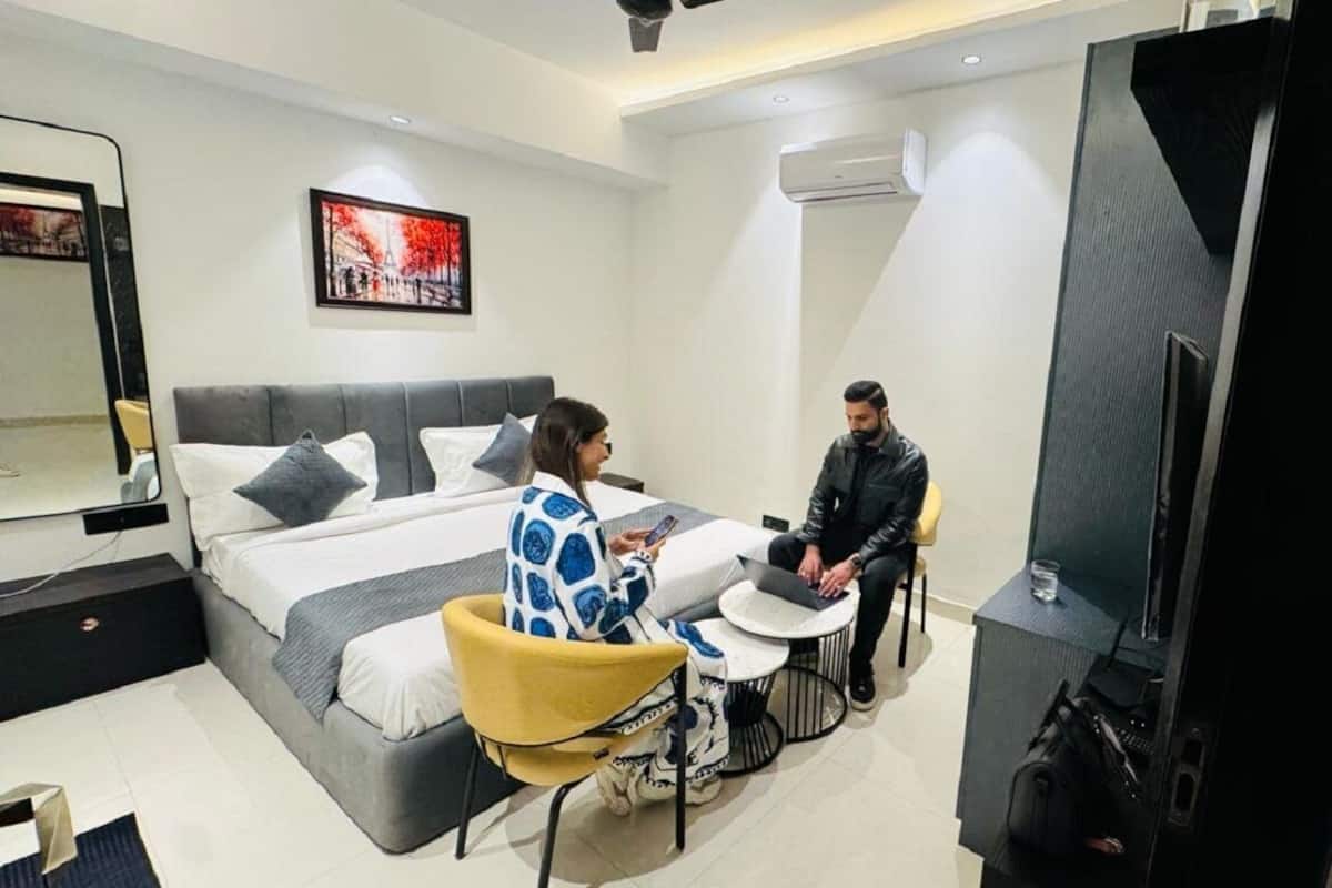 A modern hotel room with a bed, a small round table, a chair, and a television.