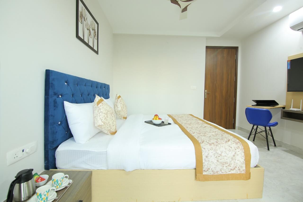 A hotel room with a bed, a desk, a chair, and a door.