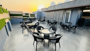 A rooftop terrace with round tables and chairs, a water tank, and a sign that reads "REEBAI". - Reebah Inn & Suites (Gurugram)