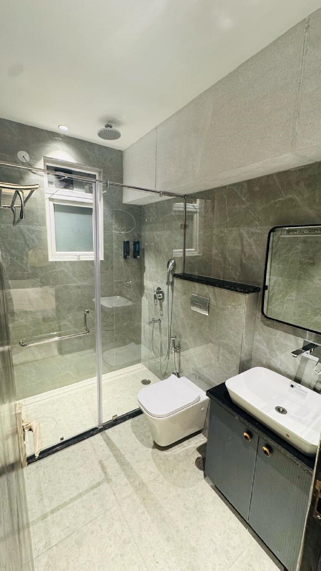 Un baño moderno con cabina de ducha de vidrio, inodoro blanco y tocador con espejo.