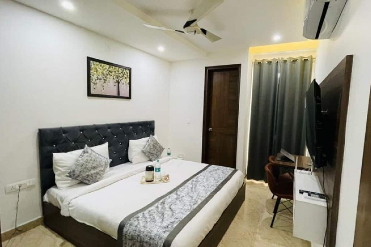 A hotel room with a bed, a desk, a chair, a TV, and a ceiling fan.