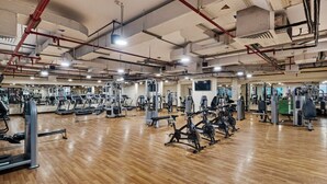 Une salle de sport spacieuse équipée de divers appareils d’exercice, notamment des tapis de course, des vélos d’appartement et des appareils de musculation.