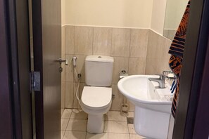 A small, clean bathroom with a toilet, sink, and mirror. - Modern 1BR in JVC, 2 Baths, Pool & Gym, Fully Equipped Kitchen (Dubai)
