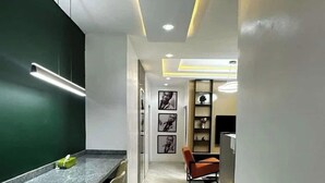 Eine moderne Küche mit Marmorarbeitsplatte, einem Essbereich mit Stühlen und einem Kühlschrank.