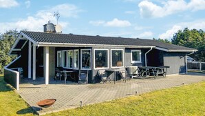 Une maison moderne dotée d’un patio couvert, de grandes fenêtres et d’une antenne parabolique.