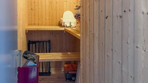 L’intérieur d’une cabane en bois, avec des toilettes blanches, une chaise bleue et un meuble rouge.