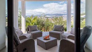 A balcony with wicker furniture, a tray with drinks, and a scenic mountain view.