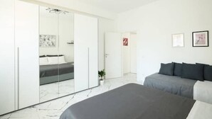 A modern bedroom with a large bed, a wardrobe, and a small plant. - Elmi 1 – Cool apartment with on-site parking  (Arona)