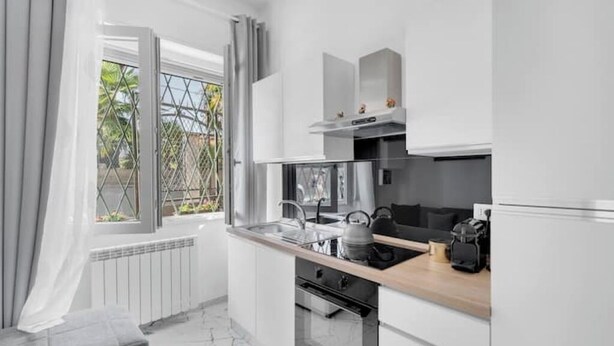 A modern kitchen with white cabinets, a wooden countertop, and a window with curtains. - Elmi 1 – Cool apartment with on-site parking  (Arona)