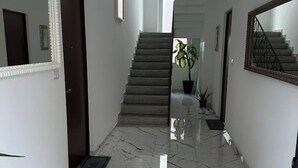 A hallway with a marble floor, a staircase, and a potted plant. - Elmi 1 – Cool apartment with on-site parking  (Arona)
