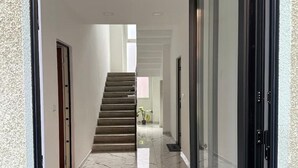 Un couloir moderne avec un sol en marbre, un escalier et une porte sur le côté droit.