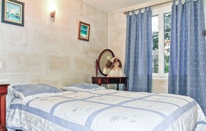 Ein Schlafzimmer mit einem Bett, einem Schminktisch, einem Spiegel und einem Fenster mit Vorhängen.