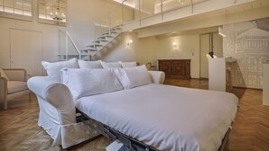 Un dormitorio amplio con una cama grande, una escalera y vistas a un paisaje urbano.