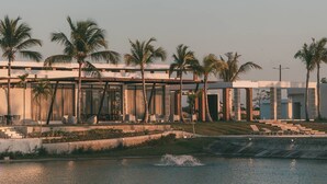 Un hotel moderno con piscina, palmeras y cielo despejado.
