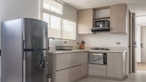 A modern kitchen with a stainless steel refrigerator, wooden cabinets, a microwave, and a built-in oven. - NOK Stylish Studio w Balcony in Laureles Medellin (Medellín)
