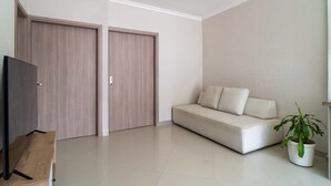 Una sala de estar moderna con un sofá, un televisor y una planta en maceta.