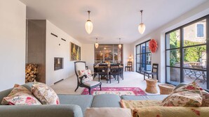 Een moderne woonkamer met een bank, stoelen, een eettafel en een groot raam met uitzicht op de omgeving.