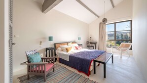 Een slaapkamer met een bed, een stoel, een tafel en een raam.