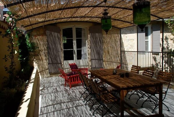 An outdoor patio with a wooden table and chairs, a thatched roof, and hanging lanterns. - Villa Vilo Your Paradise in the Heart of Alpilles (Mouries)