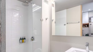 Un bagno moderno con doccia vetrata, un water bianco e un mobile vanitario in legno con specchio.