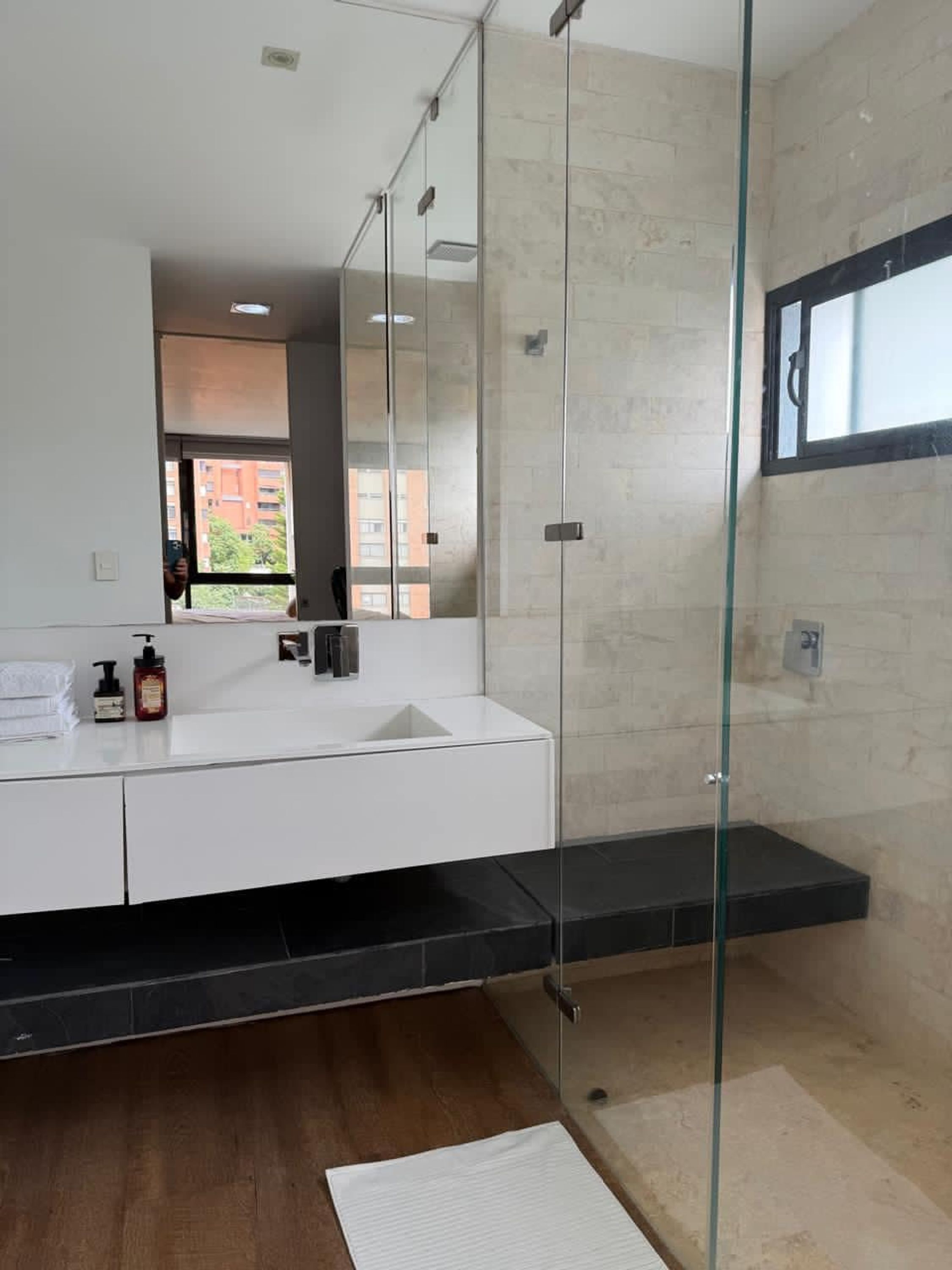 A modern bathroom with a glass shower enclosure, a white sink, and a large mirror.