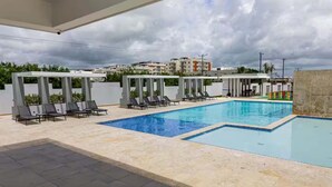A modern outdoor pool area with lounge chairs and a covered seating area. - NOK Designer 2BR Loft Jardines 3 Punta Cana (Punta Cana)