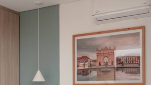 A neatly made bed with white linens, a white pendant light, and a framed picture of a bridge on the wall. - NOK Perfect 1BR in Laureles Medellin (Medellín)