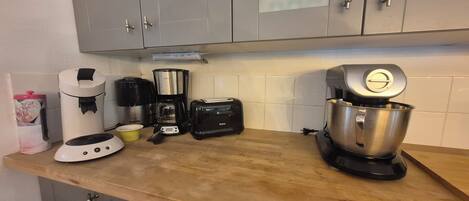 Una cocina con gabinetes grises, cafetera, tostadora y batidora.