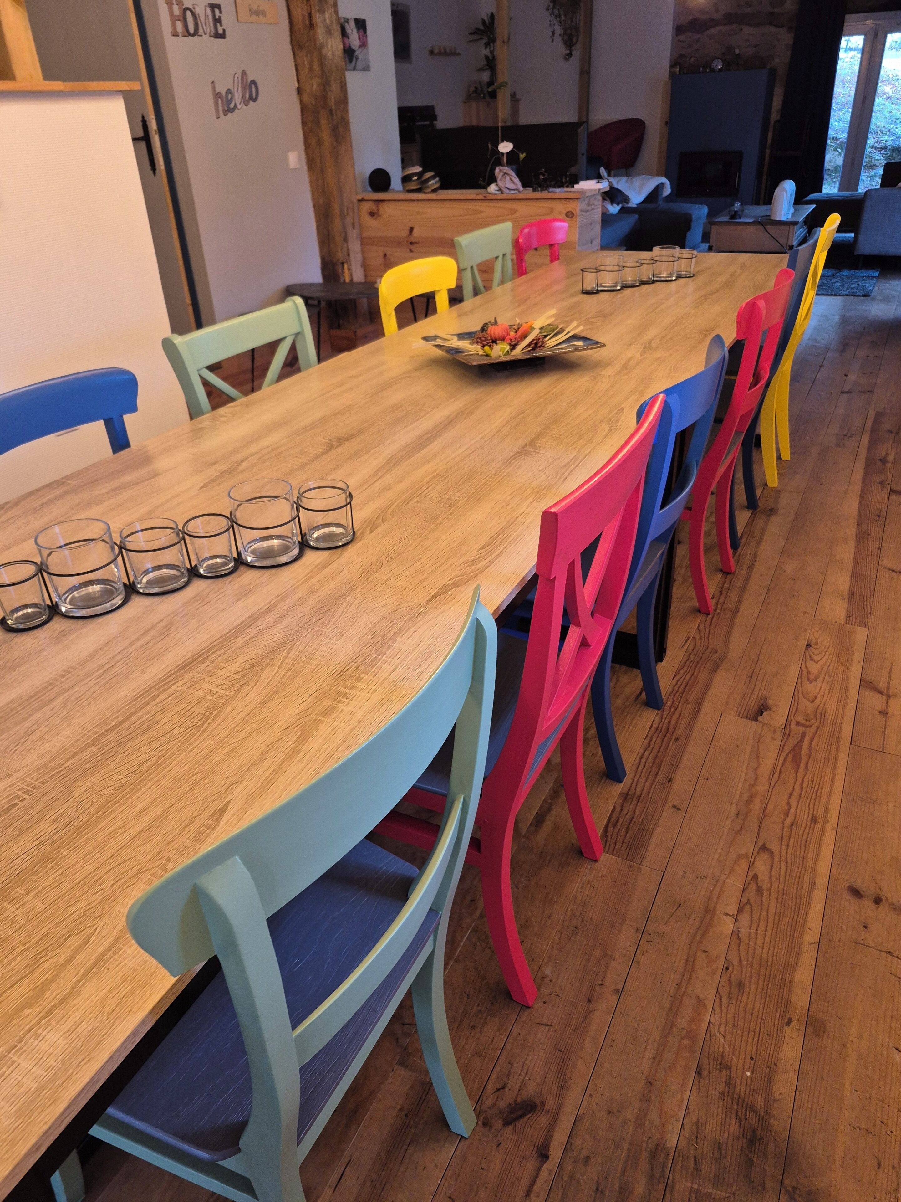 A dining area with a wooden table and colorful chairs.
