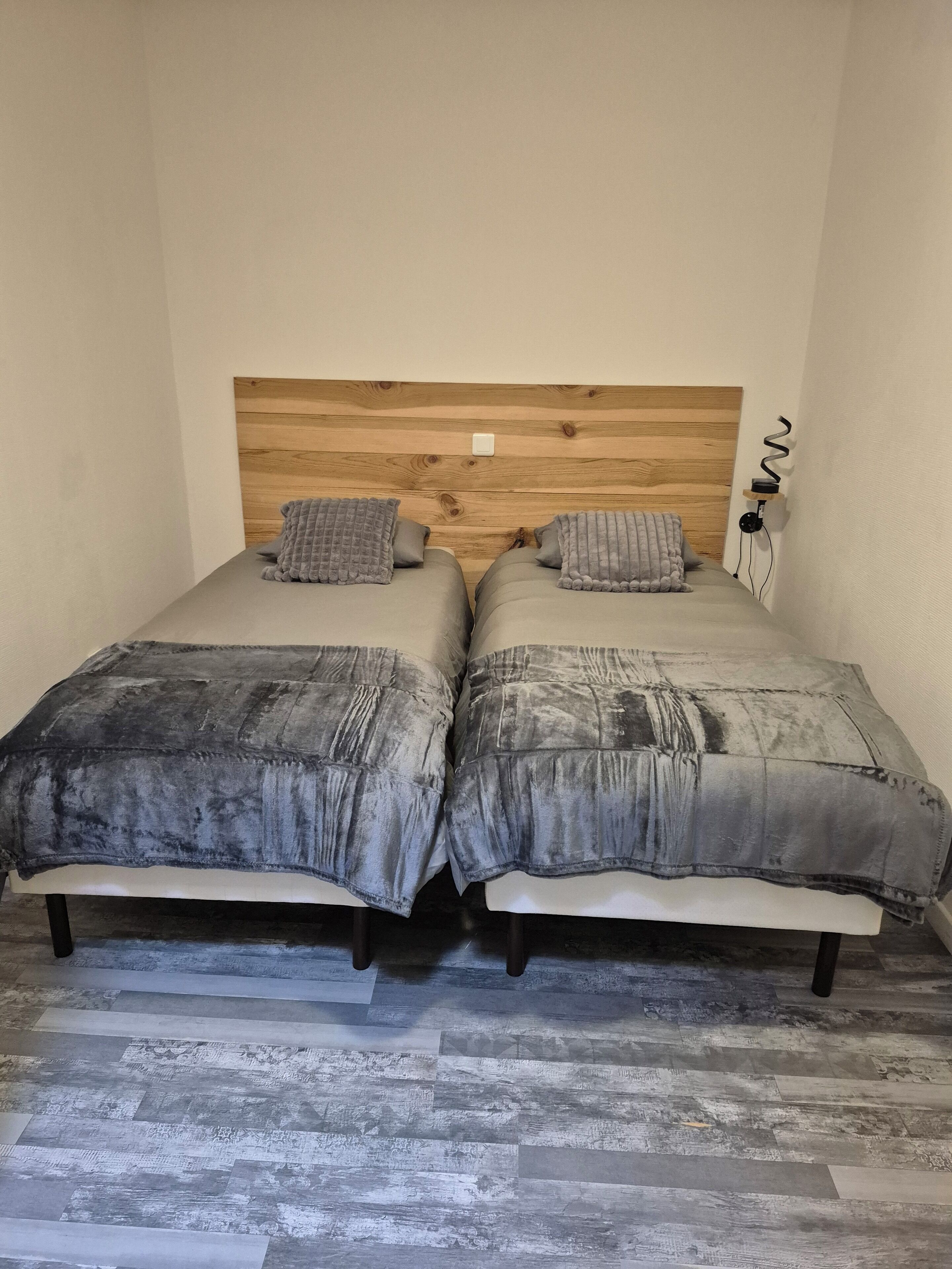 Una cama doble con cabecera de madera, dos almohadas y una colcha.