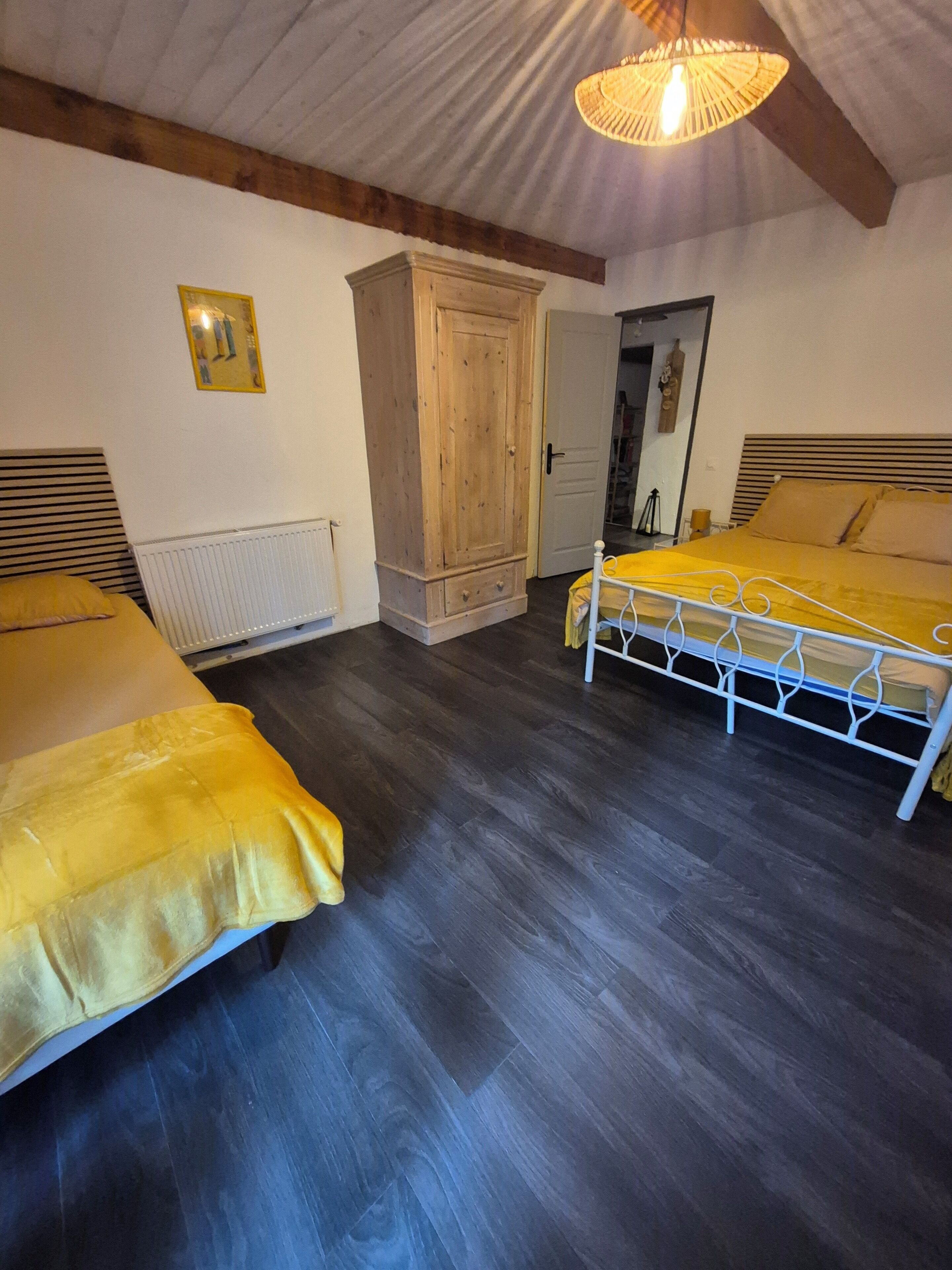 A bedroom with two beds, wooden wardrobe, and a radiator.