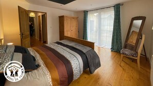 A bedroom with a bed, a wooden wardrobe, a mirror, and a window with curtains. - Renovated 3-bedroom cottage in Damvix with Wifi (Damvix)
