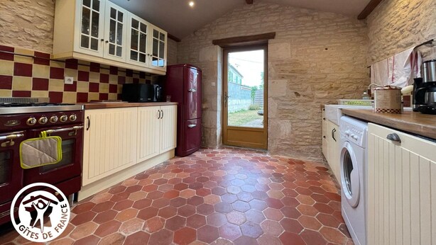 A kitchen with a stone wall, a red and white checkered backsplash, a skylight, a red refrigerator, a stove, and a washing machine. - Renovated 3-bedroom cottage in Damvix with Wifi (Damvix)