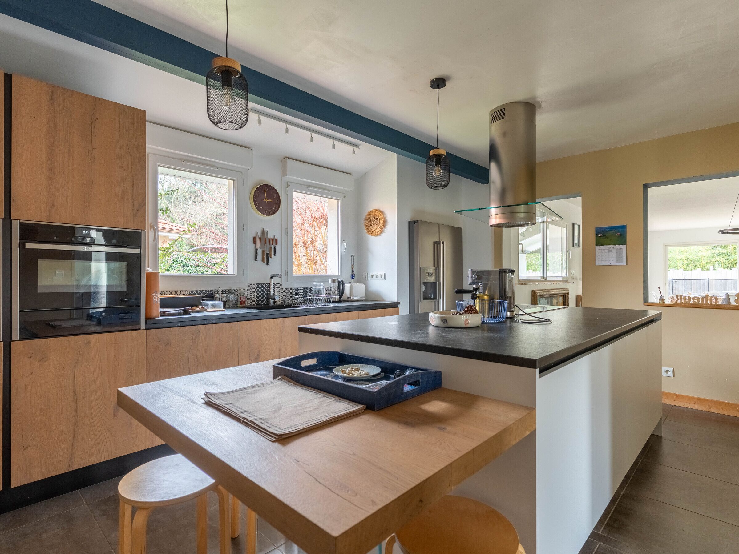 A modern kitchen with wooden cabinets, stainless steel appliances, and a central island with stools.