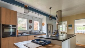 Eine moderne Küche mit Holzschränken, Edelstahlgeräten und einer zentralen Kochinsel mit Barhocker.