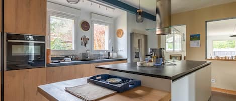 A modern kitchen with wooden cabinets, stainless steel appliances, and a central island with stools.