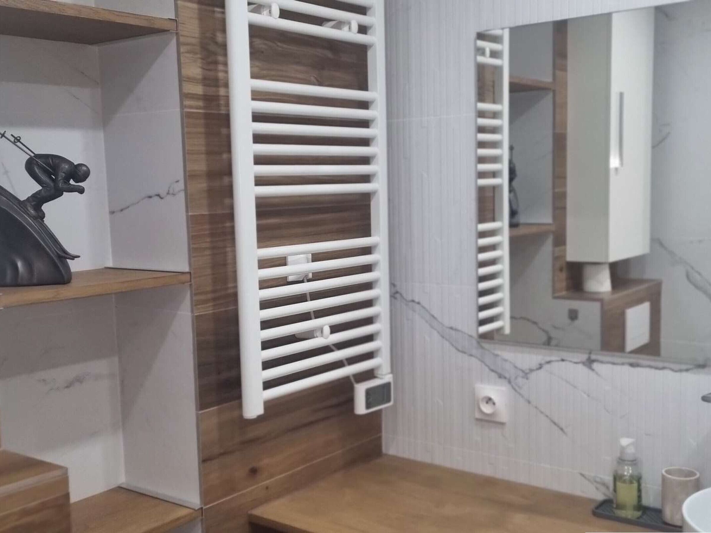 Une salle de bain moderne avec un meuble-lavabo en bois, un radiateur blanc et un pare-feu en marbre.
