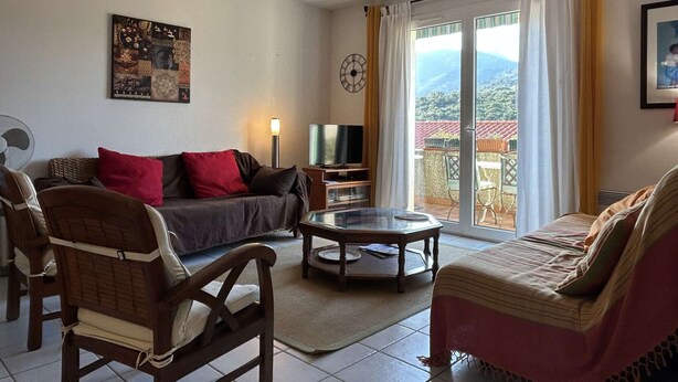 A living room with a sofa, armchairs, a coffee table, a TV, and a balcony with a view of the mountains. - Family house 4 rooms 8 people, near the beach in Banyuls-sur-Mer (Banyuls-sur-Mer)