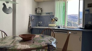 A kitchen with a dining table, chairs, a window with a view, and a sink. - Family house 4 rooms 8 people, near the beach in Banyuls-sur-Mer (Banyuls-sur-Mer)