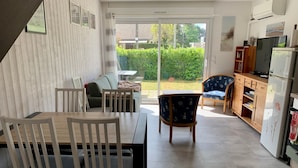 A modern kitchen with a dining area, a sofa, and a view of the garden. - Family home between beach and bay with private parking (Fort-Mahon-Plage)