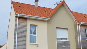 A two-story residential building with a red-tiled roof, beige walls, and wooden siding. - Family home between beach and bay with private parking (Fort-Mahon-Plage)