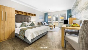 A hotel room with a bed, a desk, a chair, a wardrobe, and a view of the outside. - “Apartment Föhr” in the heart of Büsum with balcony, centrally located and close (Büsum)