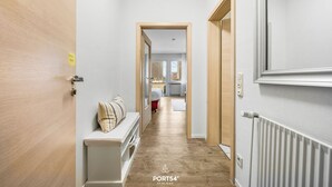 Un couloir avec une porte en bois, un banc doté d’un coussin et un radiateur.
