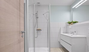 A modern bathroom with a glass shower enclosure, a white sink, and a mirror. - “Apartment Amrum” in the heart of Büsum with balcony, centrally located and clos (Büsum)