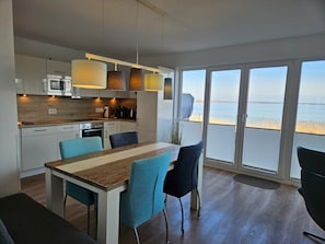 A modern kitchen with a dining area, large windows, and a view of the sea. - WeitBlick - Sea view, 2 terraces, private parking space, infrared cabin (Olpenitz)