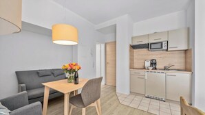 A compact living space with a sofa, dining table, and kitchenette. - "Ferienwohnung Krebs" in the heart of Büsum with balcony and close to the beach (Büsum)